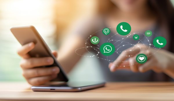 A photorealistic image showing only a girl's hand using a smartphone, with social media icon popups floating around the mobile, including Facebook, Instagram, WhatsApp, YouTube, and Twitter icons. The background is softly blurred, highlighting the hand and phone, bright natural lighting, close-up shot,